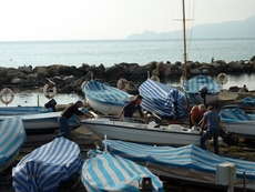 Men cover the boats to protect them from the winter in Chiavari